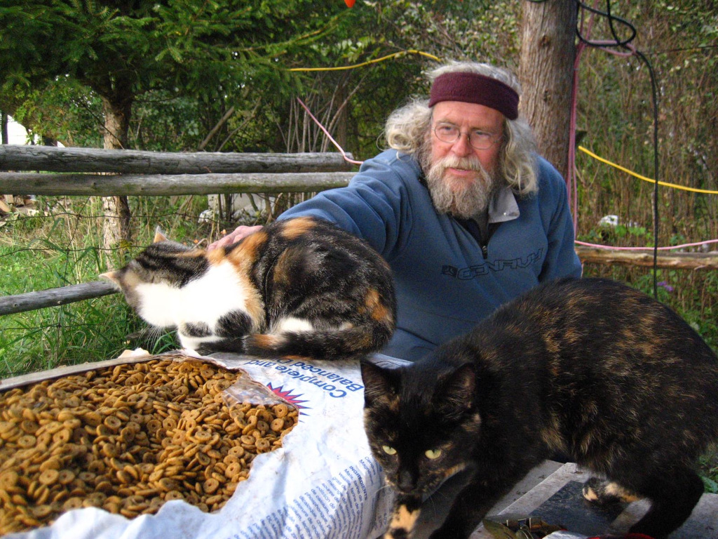 Glen Kealey, outdoors, with two of his cats