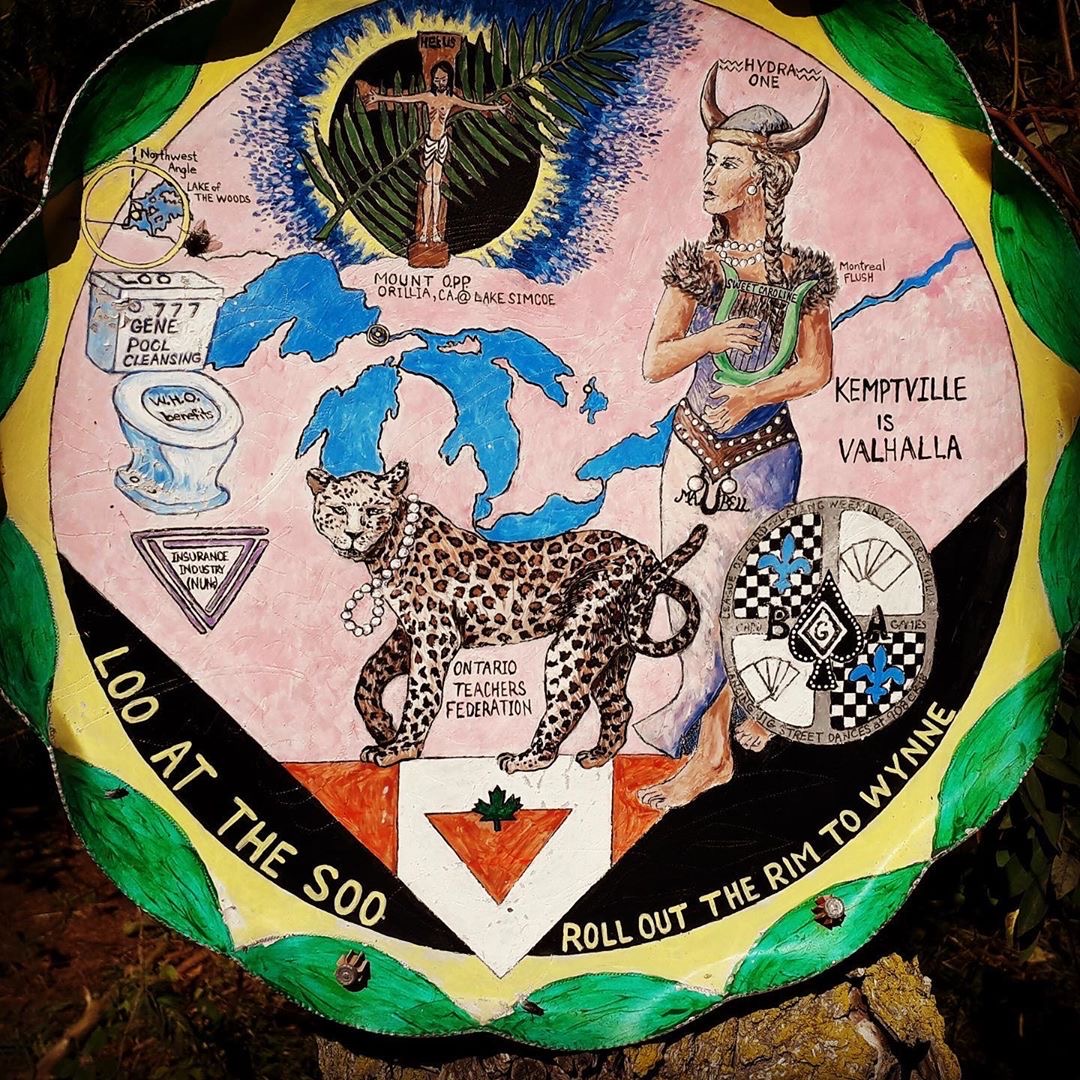 Painted disc by Jennifer Ann Kealey: a harpist in a horned helmet beside the Great Lakes, a leopard, and the painted words "Kemptville is Valhalla"